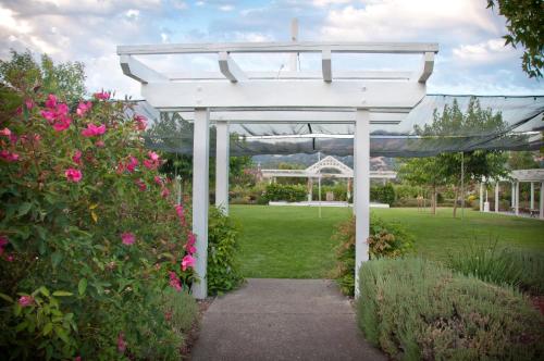 a white pergola in a garden with pink flowers at Geyserville Inn in Geyserville