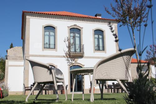 two chairs and a table in front of a building at Quinta de Fiães in Vilar de Maçada