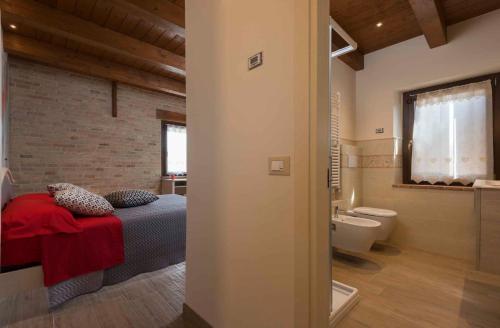 a bedroom with a bed and a bathroom with a toilet at B&B Olmo in Saludecio