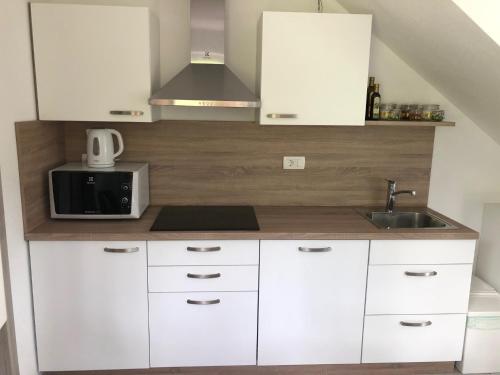 a kitchen with white cabinets and a sink and a microwave at Jack's Apartments in Bled