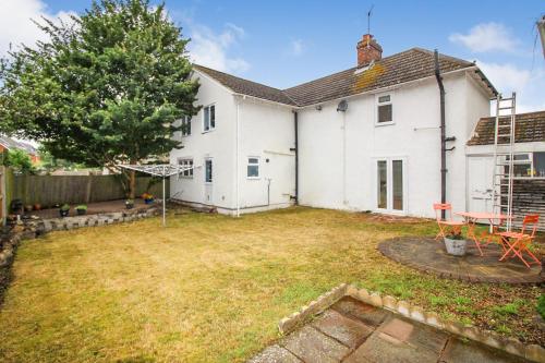 a backyard of a white house with a table and chairs at Mallard Cottage Guest House in Aylesford
