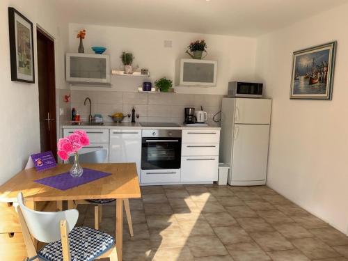 a kitchen with white appliances and a wooden table with a tableablish at Apartman Cvenkica in Omišalj