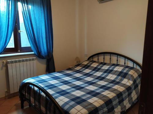 a bedroom with a bed with blue curtains and a window at Agricampolungo Monterosi in Monterosi