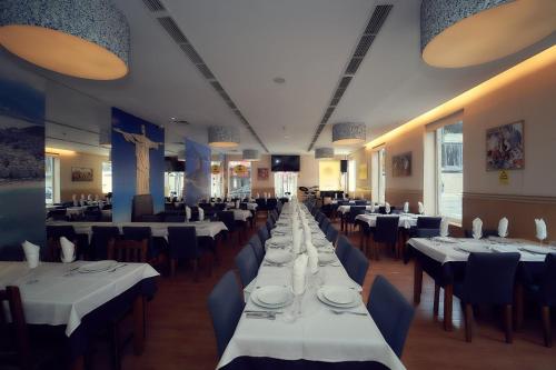 un comedor con mesas blancas y sillas azules en Hostel Matosinhos Suites, en Matosinhos