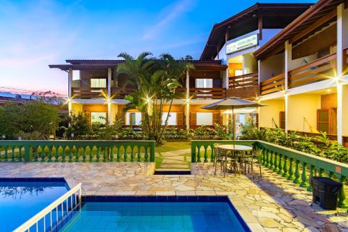 a view of a resort with a pool and a table at Pousada Vivamar in Ubatuba