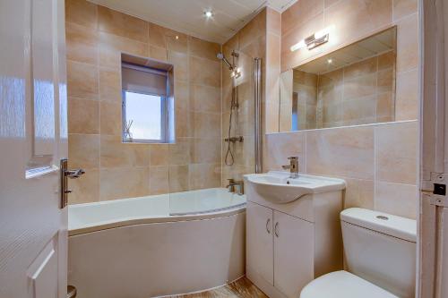 a bathroom with a toilet and a sink and a bath tub at No 7 Ayr Beach - Coorie Doon in Ayr