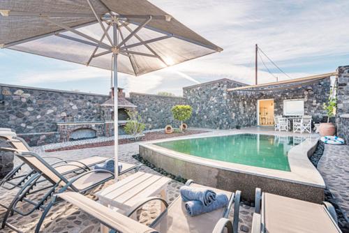 een zwembad met stoelen en een parasol bij Klimata House - Private Jacuzzi Pool & BBQ Villa in Vlychada Beach