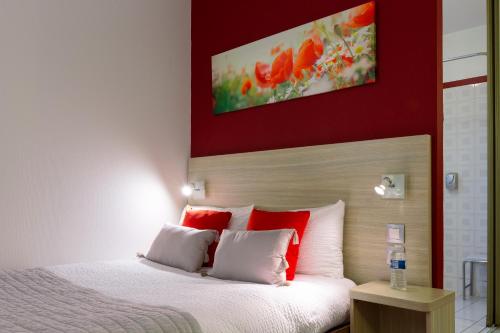 a bedroom with a bed with red and white pillows at Logis Hotel Altina in Pacy-sur-Eure
