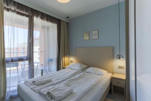 a bedroom with a large white bed with a window at Unique Motlawa Riverbank Apartment in Gdańsk