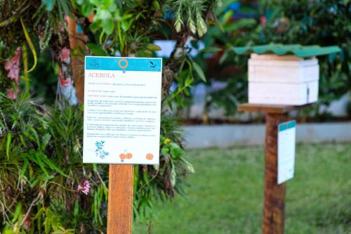 a sign in the grass next to some trees at Pousada Vivamar in Ubatuba