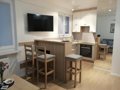 a kitchen with a bar with stools and a tv at Mieszkanie Świdnik in Świdnik