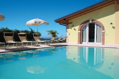 a swimming pool with chairs and an umbrella at B&B Al Cristo in SantʼAmbrogio di Valpolicella