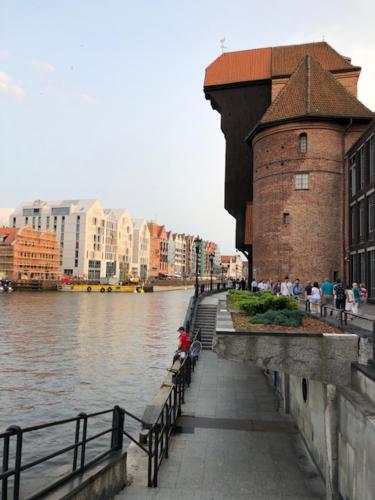a walkway next to a river next to a building at Moon River Apartments Gdansk Old Town in Gdańsk