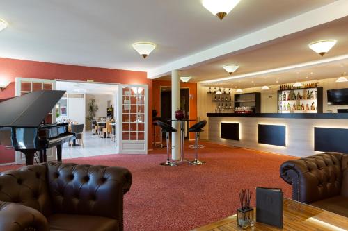 a living room with a piano and a living room with a table at Logis Hotel Altina in Pacy-sur-Eure