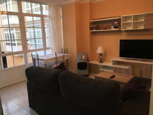 a living room with a couch and a television at Apartamento junto al paseo marítimo de Cee in Cee