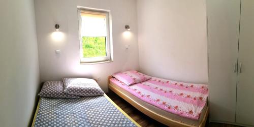 two beds in a small room with a window at Bieszczadzki Orzeł in Berezka