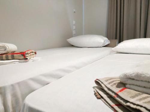 two beds in a room with white sheets and pillows at Lilly Apartments in Athens