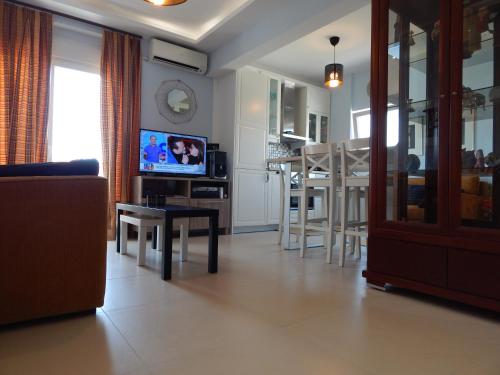 uma sala de estar com um sofá e uma mesa com uma televisão em Christina-2 em Perea