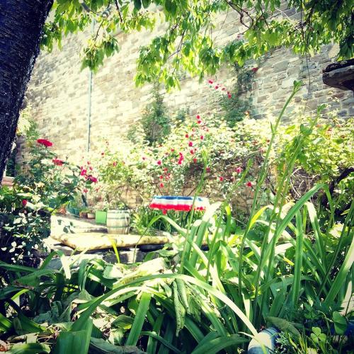 a garden with pink flowers in front of a brick wall at Morfeas Guesthouse in Papigko