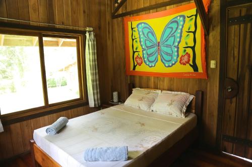 1 dormitorio con 1 cama con una pintura de mariposa en la pared en Hotel & Cabinas Nadine en Cahuita