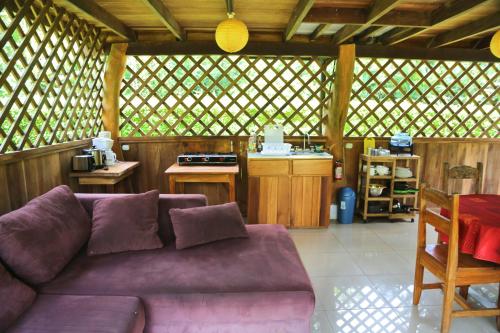 a living room with a purple couch and a kitchen at Hotel & Cabinas Nadine in Cahuita