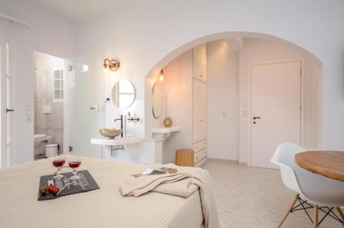 a white bathroom with a table and two glasses of wine at Smirida Suites in Naxos Chora