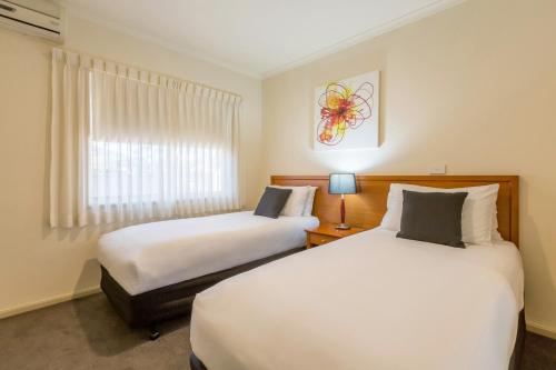 two beds in a hotel room with a window at Quest Tamworth in Tamworth