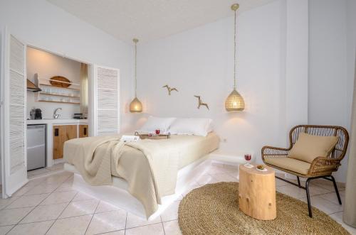 a white bedroom with a bed and a chair at Smirida Suites in Naxos Chora