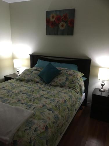 a bed in a bedroom with two lamps on tables at Down Home Accommodations in Rocky Harbour