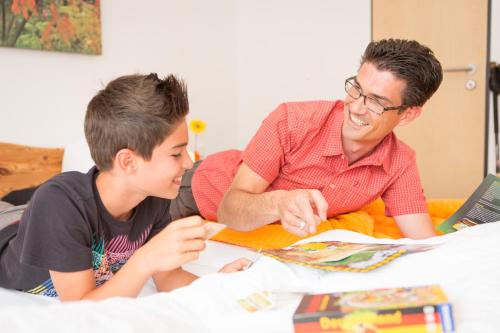 a man and a boy sitting at a table looking at a book at Hotel Emmerich in Winningen