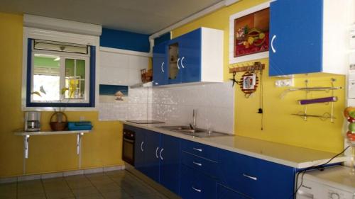 a kitchen with blue and yellow cabinets and a sink at Maison mitoyenne in Garnier