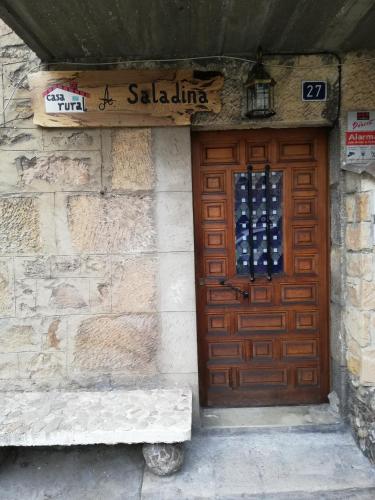 a wooden door of a building with a bench in front at Casa, rural A Saladina in Soria
