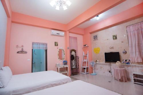 a bedroom with two beds and a flat screen tv at Rose Castle in Taitung City