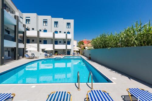 a swimming pool with chairs and a building at Yacinthos in Rethymno Town