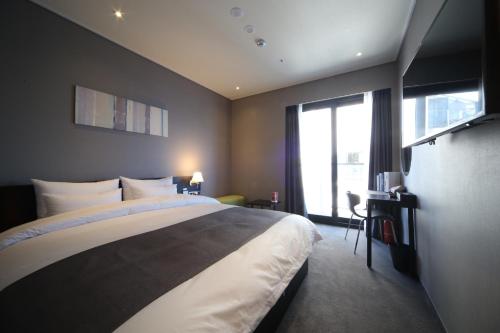 a bedroom with a large bed and a large window at Ocean The Point Hotel Busan in Busan