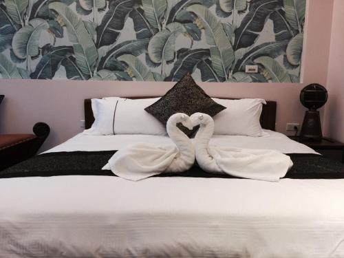 two white swans are sitting on a bed at Ciao Home in Toucheng