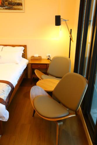 a room with two chairs and a bed and a desk at Ciao Home in Toucheng