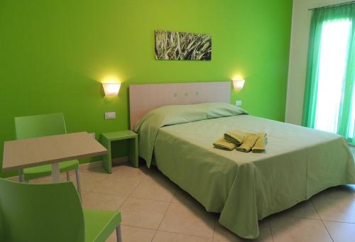 a green bedroom with a bed and a table at Arcupintau in Villasimius