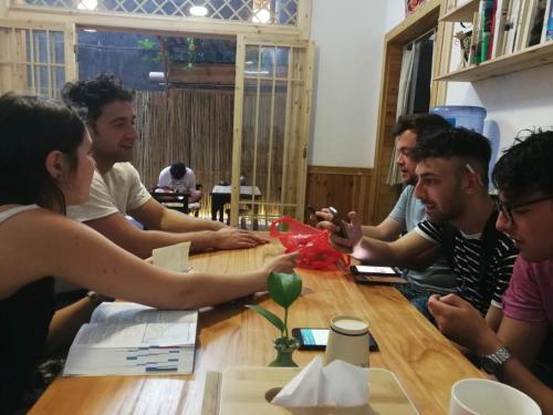 a group of people sitting around a wooden table at Hemu House in Fenghuang