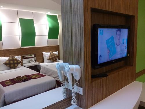 pokój hotelowy z 2 łóżkami i telewizorem z płaskim ekranem w obiekcie The Camelot Hotel Pattaya w Pattaya South