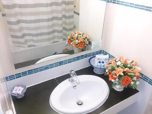 a bathroom with a sink and a mirror and flowers at The Camelot Hotel Pattaya in Pattaya South