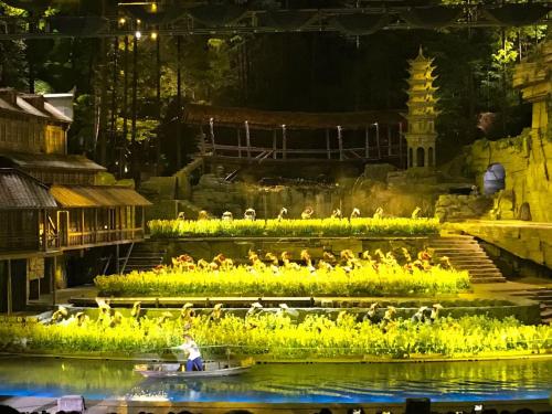 a person in a boat with birds on the water at Hemu House in Fenghuang