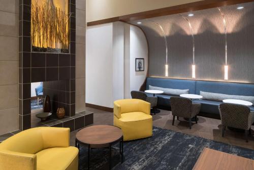 a waiting room with yellow chairs and tables at Hyatt Place Jacksonville Airport in Jacksonville