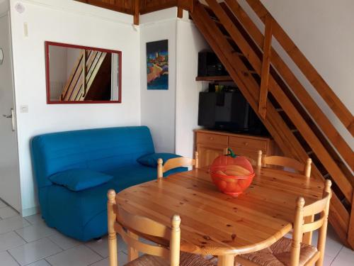 une salle à manger avec une table et un canapé bleu dans l'établissement 43-2 LES MAISONS DU RIVAGE BLEU, à Gruissan