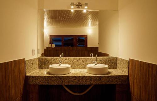 La salle de bains est pourvue de 2 lavabos et d'un grand miroir. dans l'établissement Pousada Brésil Aventure, à Galinhos