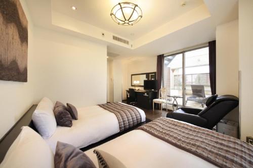 una habitación de hotel con 2 camas y una silla en Hotel Coco Grand Kitasenju, en Tokio