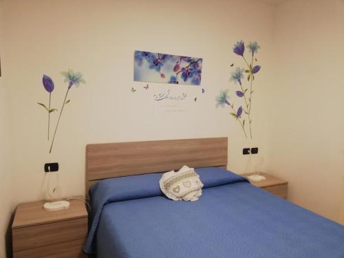 a bedroom with a blue bed and flowers on the wall at Cà delle Rose in Rovereto