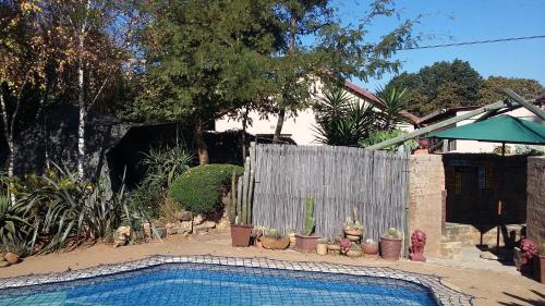 Una piscina frente a una valla con plantas. en Blyde Guesthouse, en Benoni