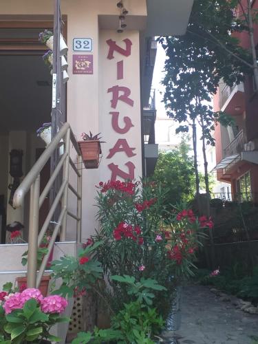 a sign on the side of a building with flowers at Nirvana Guest House in Nesebar