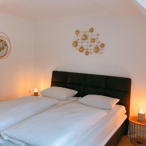 a bedroom with a bed with white sheets and two candles at Gästehaus Ehebachhof Hotel Garni in Müllheim